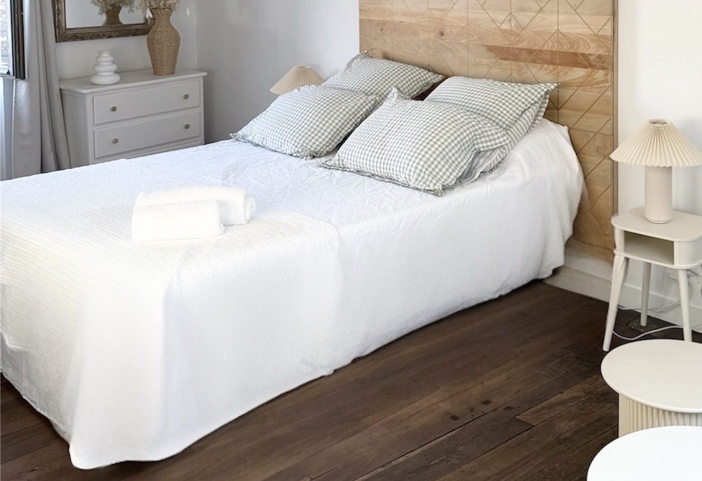 Le lit de la suite Saint-Pierre à Poitiers Lit queen size de la suite Saint-Pierre à Poitiers, avec linge blanc, tête de lit en bois, commode et parquet ancien.
